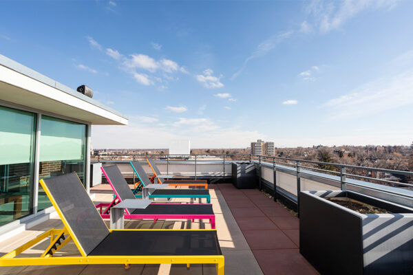 Rooftop patio with colorful lounge chairs overlooking Denver.