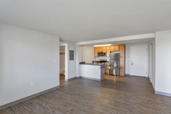 Living room with wood floor and white walls with kitchen.