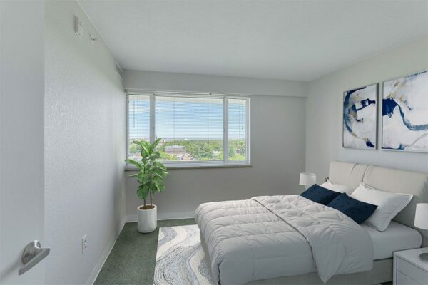 Bedroom with plush bed, framed artwork, and large window.