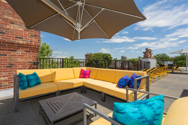 Detail of plush outdoor sectional with umbrella on rooftop patio.