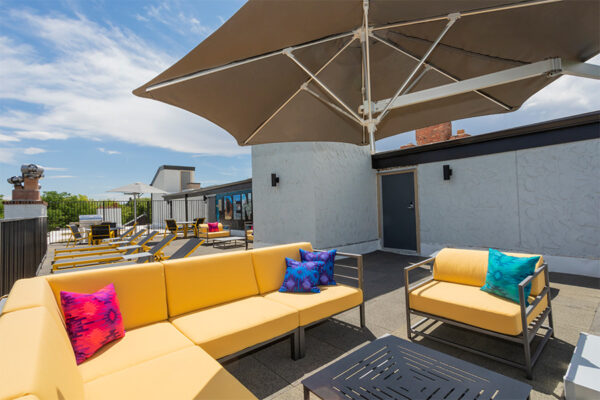 Detail of plush outdoor sectional with umbrella on rooftop patio.
