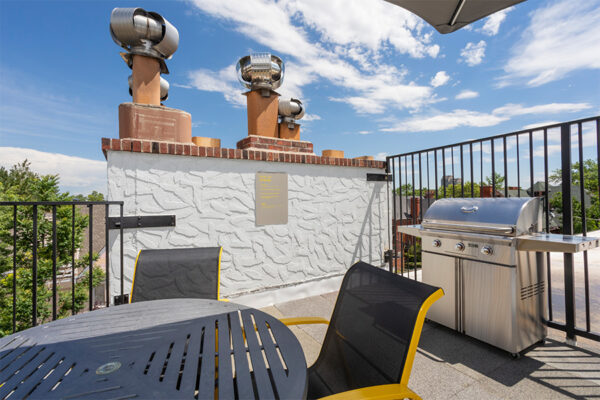 Rooftop patio with dining table, metal railings, and built in BBQ grill.