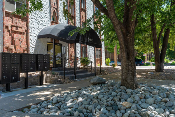 1402 Race entrance with mailboxes, mature trees, and rocky landscaping.