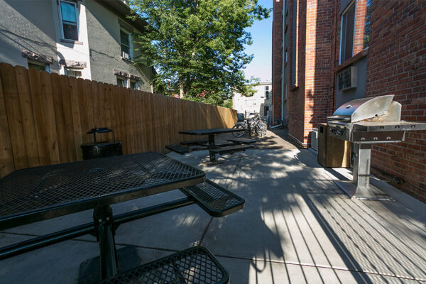 Patio at 1430 Humboldt with built in picnic tables and BBQ grills under shady trees.