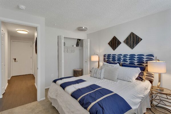 Bedroom with plush bed, bedside tables with lamps, and doors to closet and hallway.