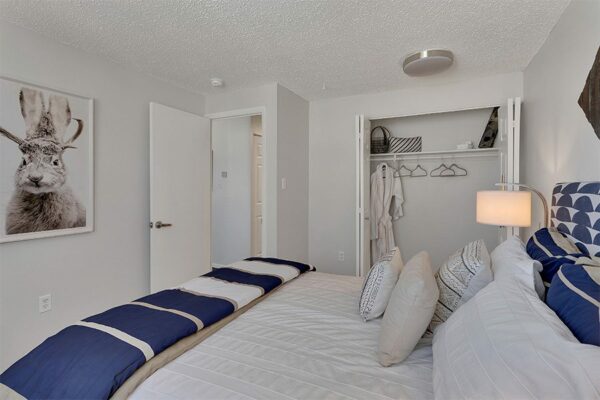 Bedroom with plush bed, framed jackalope photo, and door to closet and hallway.