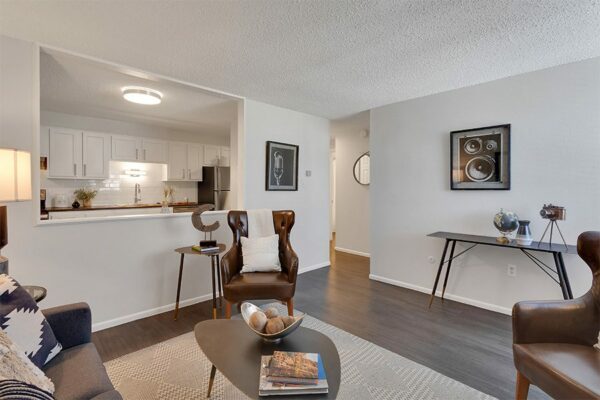 Living room with wood floor, plush rug, comfortable seating, and half wall to kitchen.