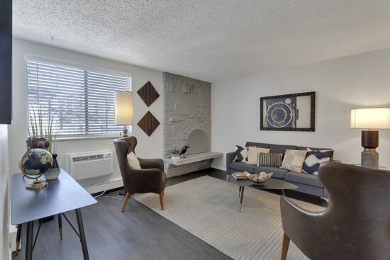 Living room with wood floor, rug, modern furniture, and brick fireplace.