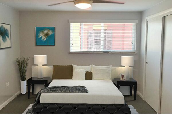 Bedroom with plush bed, bedside tables with lamps, framed artwork, and large window.