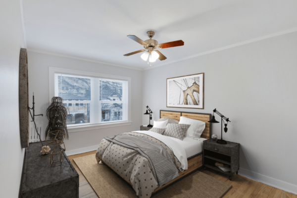 bedroom with bed in the center, ceiling fan, large dresser and window.