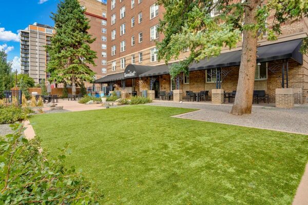 The Novelist front lawn with lush green grass, rocky landscaping, and mature trees.
