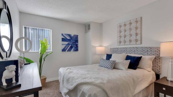 Bedroom with carpet, plush bed with headboard, large round mirror, and artwork.