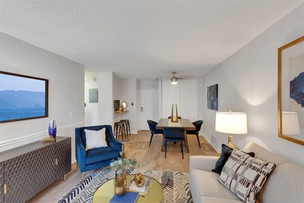 Living room with wood floor, large rug, plush seating, eclectic furniture, and modern dining table.
