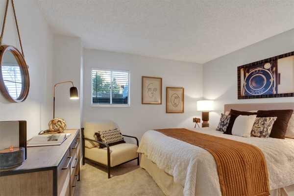 Bedroom with plush carpet, large bed, wood furniture, and framed artwork.