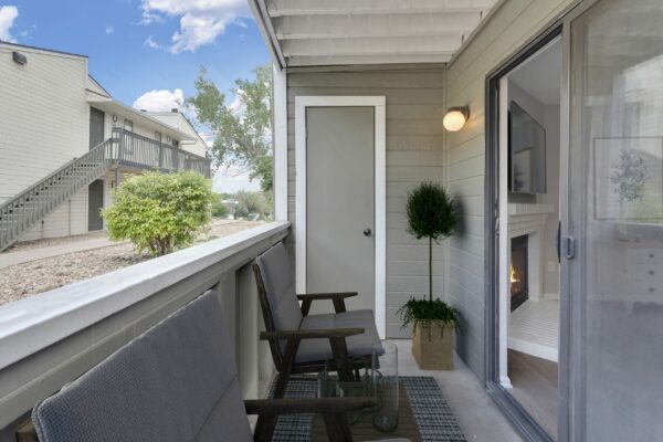 Balcony with plush chairs, potted plant, and door to living room.