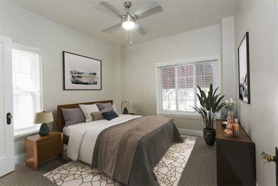 Bedroom with plush rug, large bed, and bedside tables with lamps.