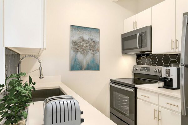 Kitchen with white counters and cabinets and gray appliances.