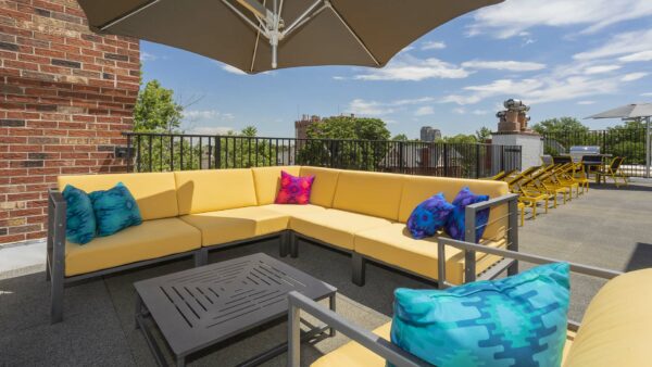 Rooftop patio with plush outdoor furniture, umbrellas, and metal railings.