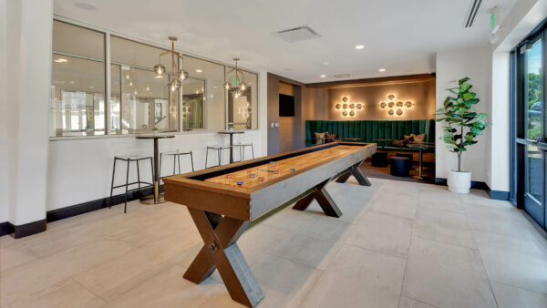 Game room with shuffleboard table, bar tables with stools, and lounge with booths and TV.