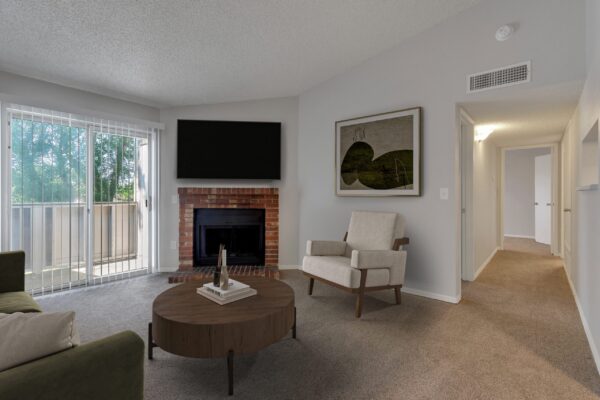 living room with fire place, couches, coffee table and sliding door to balcony