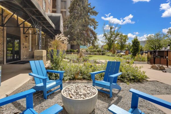 blue chairs surrounding outdoor fire pit in front of Novelist apartments