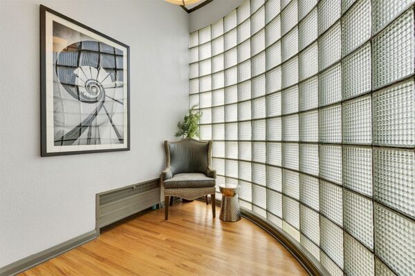 Room with glass brick walls, wood floor, and vintage chair.