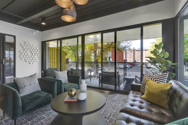 Lounge with geometric carpet, plush seating, eclectic decor, and large window.