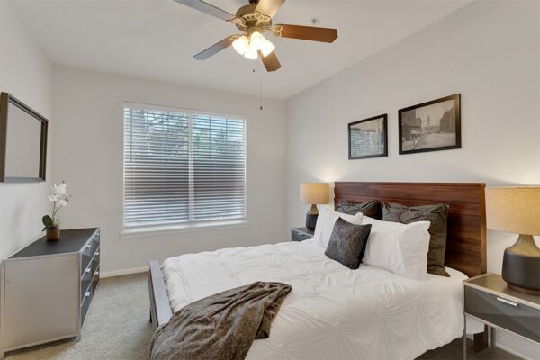 Apartment bedroom with queen size bed and window.