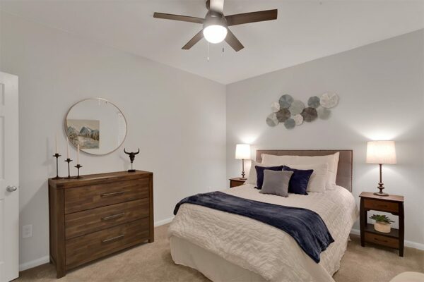 Apartment bedroom with queen size bed and dresser.