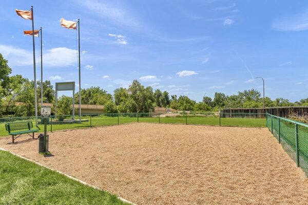 Fenced dog park with gravel play area and benches.