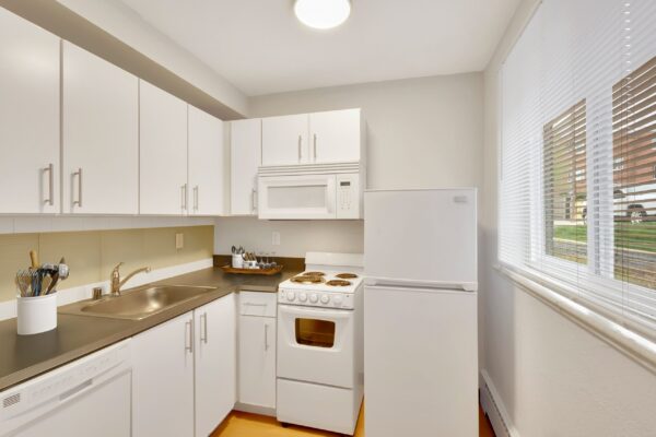 L kitchen with white cabinets and small oven