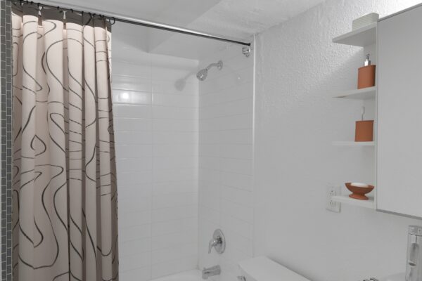 bathroom with white cabinets and countertops, toilet, and bathtub