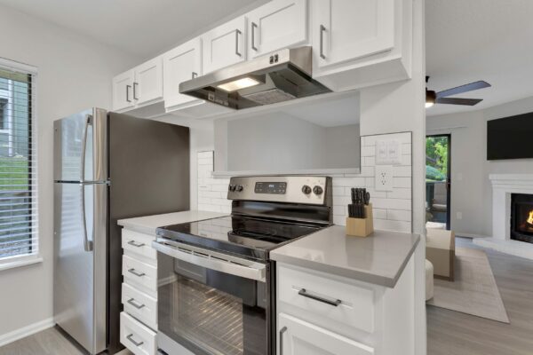 Kitchen with white cabinets, grey counters, stainless steel appliances, and tiled backsplash.