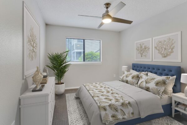 Bedroom with plush bed, dresser with eclectic decor, framed artwork, and ceiling fan.