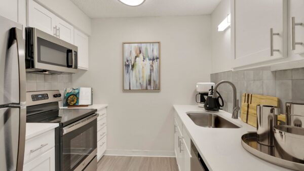 Kitchen with white countertops, white walls, and stainless steel appliances.