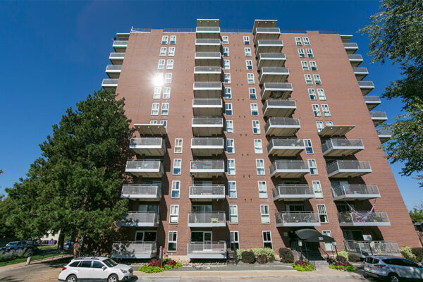 515 Clarkson apartment exterior with large balconies and lush trees.