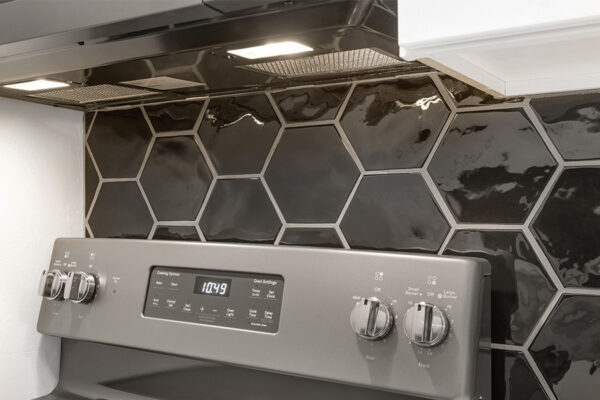 Kitchen detail with dark grey range and hexagon tiled backsplash.