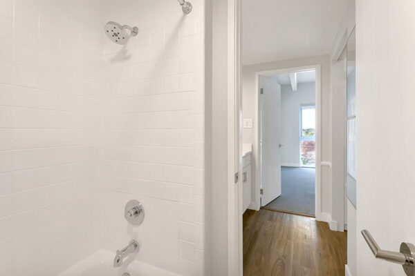 Bathroom with tiled shower tub and door to apartment hallway and bedroom.