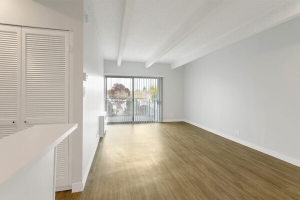 Living room with wood floors, cool gray walls, and sliding door to balcony.