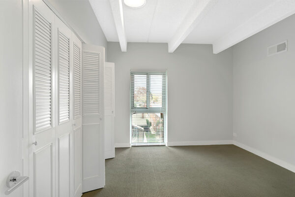 Bedroom with carpet, large closet doors, and large window.