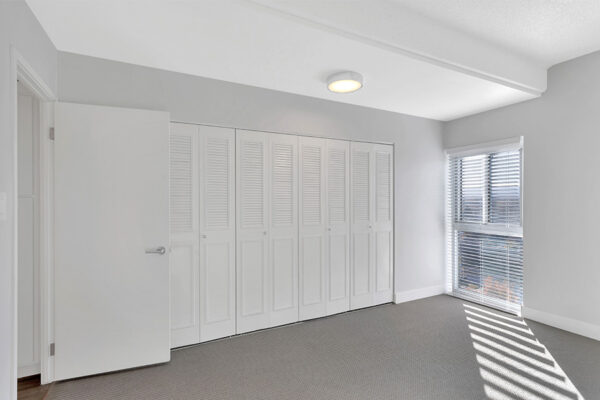 Bedroom with carpet, large closet door, and large window.