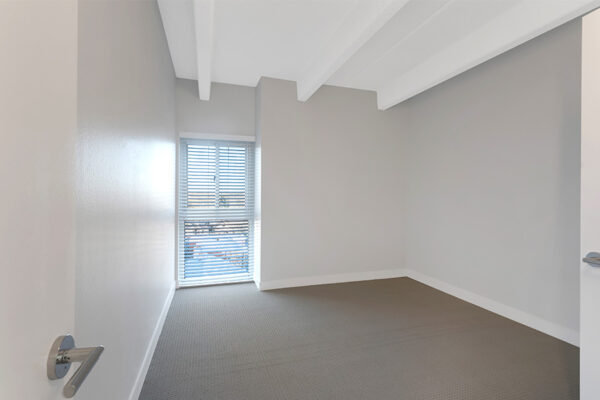 Bedroom with carpet, cool gray walls, and large window.