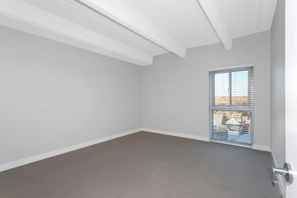 Bedroom with carpet, cool gray walls, and large window.