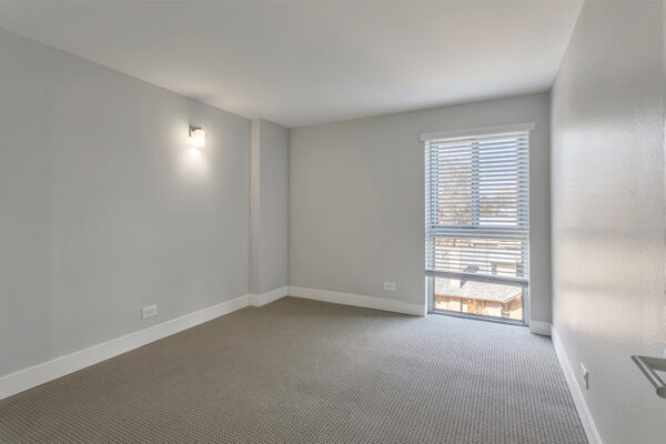 Bedroom with carpet, cool gray walls, and large window.