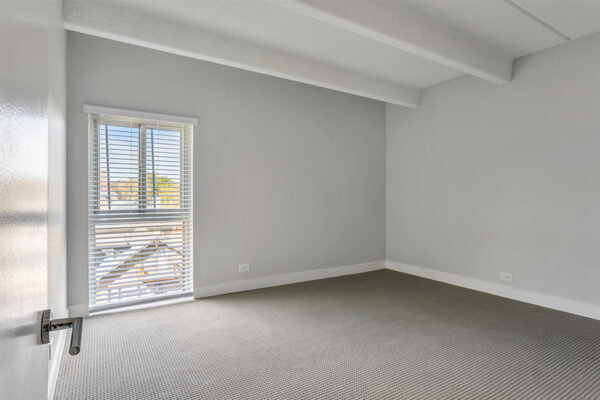 Bedroom with carpet, cool gray walls, and large window.