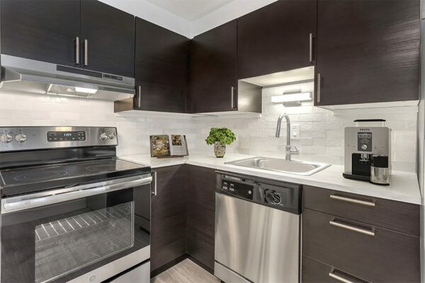Kitchen with dark cabinets, white countertops, and stainless steel appliances.