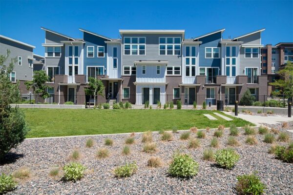 Platt Park townhomes with lush green lawns, iron fence, and tall trees.