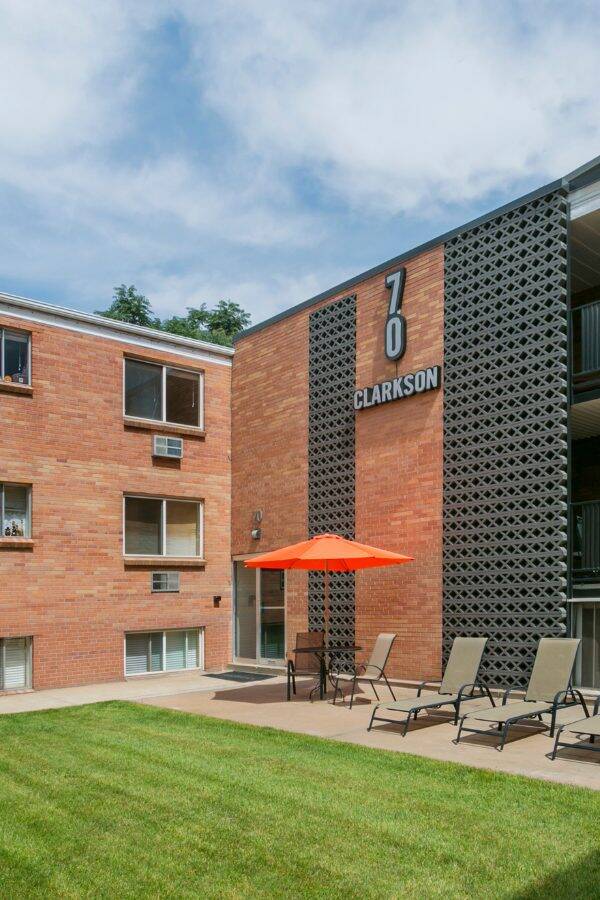 exterior of 70 Clarkson apartments and green lawn with lawn chairs