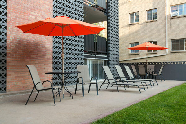 70 Clarkson apartment courtyard with lounge chairs and umbrellas overlooked by apartment balconies.