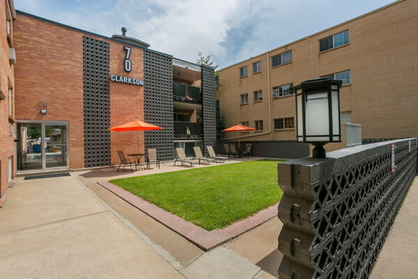 70 Clarkson apartment courtyard with lounge chairs and lawn overlooked by apartment balconies.